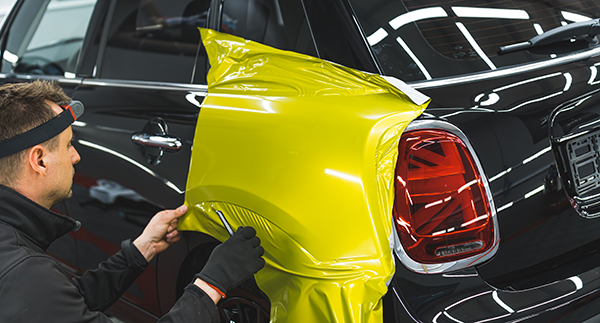 Man wrapping a car in a plastic film as a paint alternative