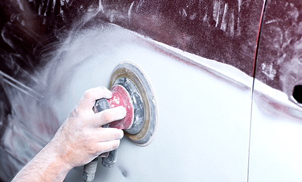 Person with an electric sander, sanding  a car door