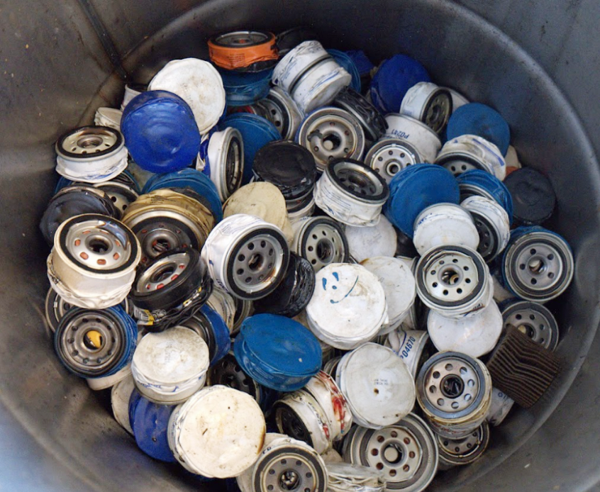 Image of used oil filters crushed down and stored in a metal drum